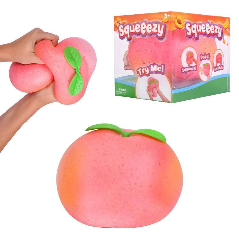 Le Sage May jumbo peach sensory stress ball being squeezed by hands next to its retail packaging box